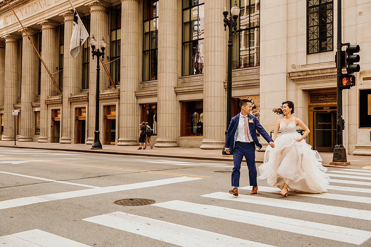 newlywed couple running across the street in front of the board of trade in chicago