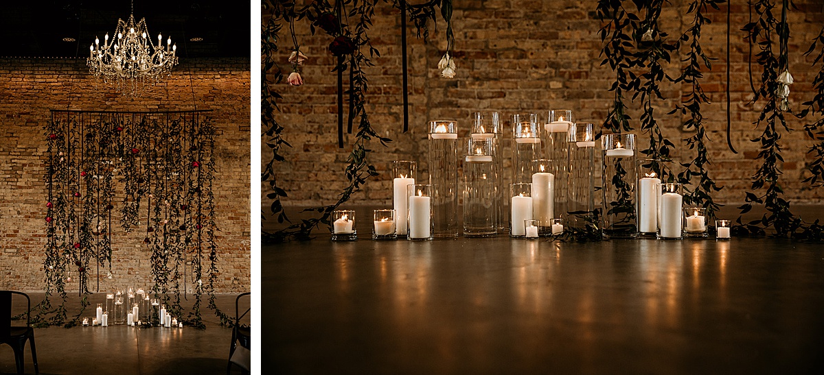 Ceremony decor in a brick industrial building decorated with candles and hanging florals.