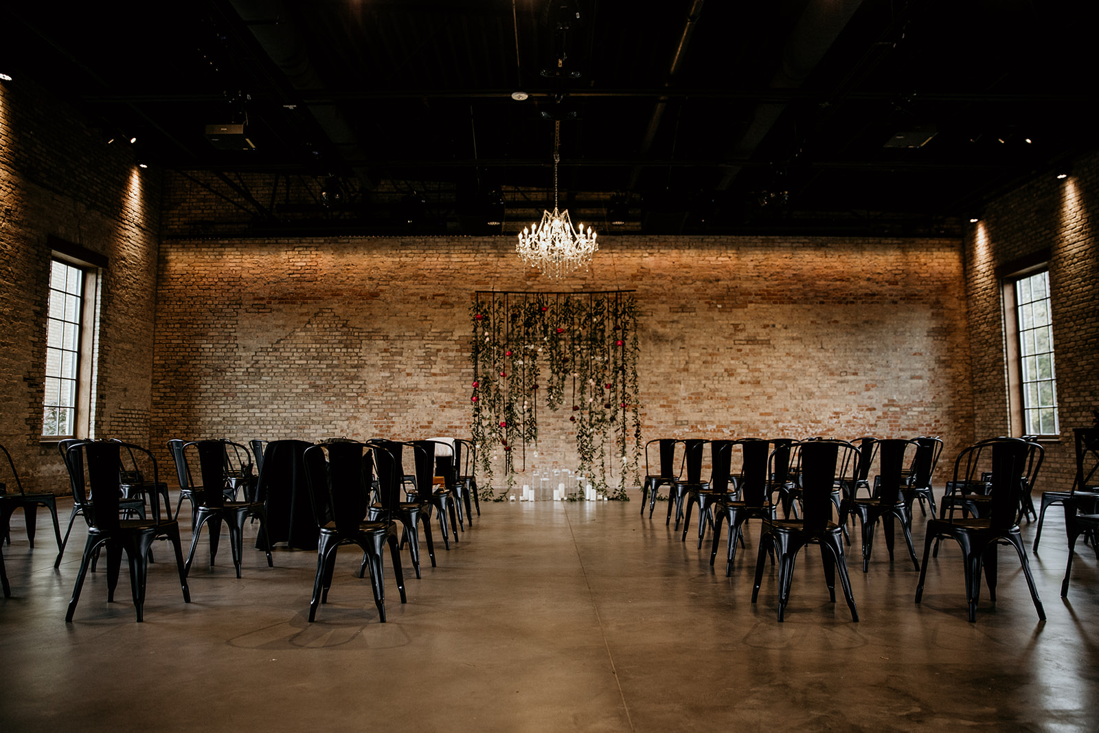 industrial wedding venue ceremony space decorated with hanging florals and candles