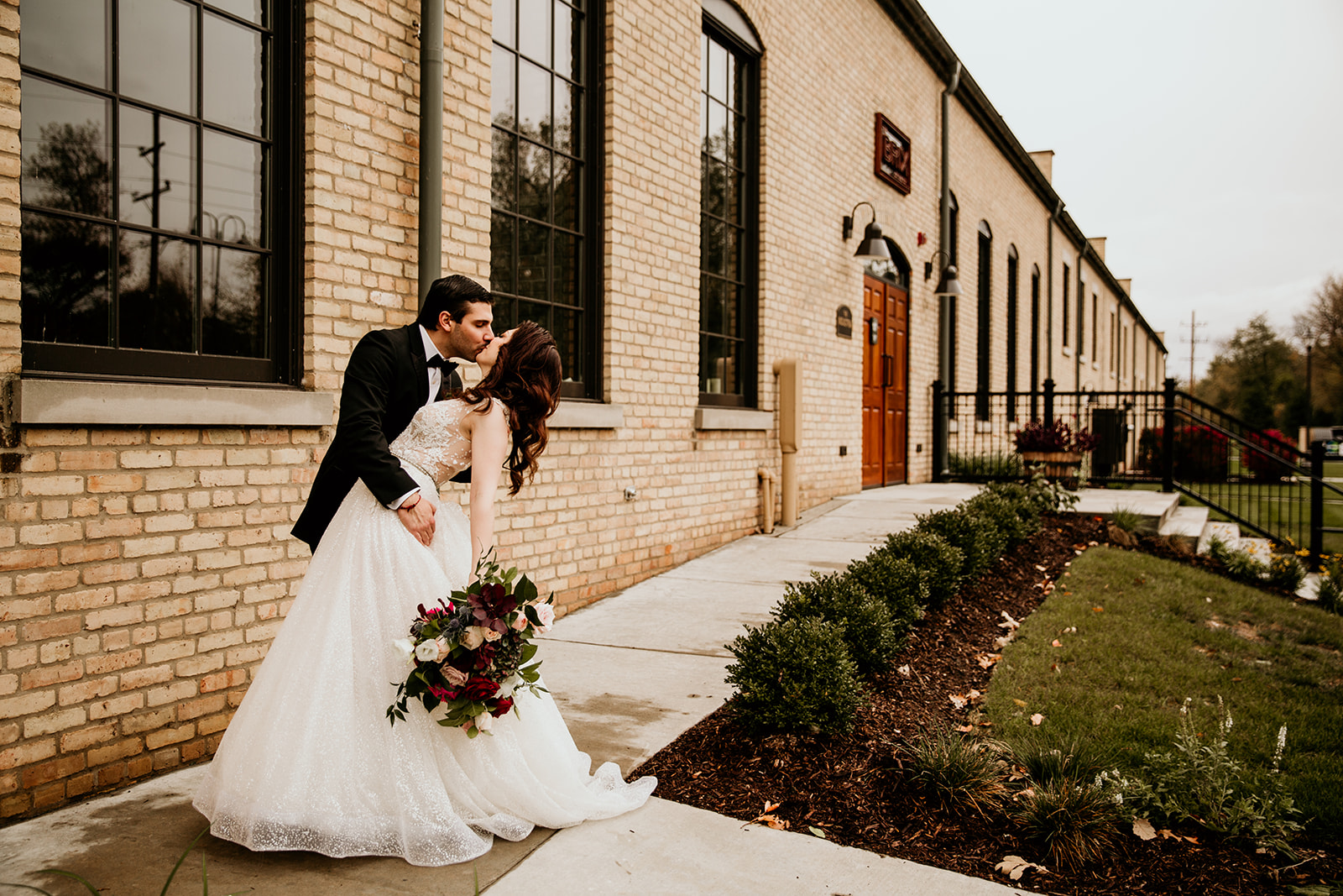 Bride and groom kissing outside of their industrial wedding venue.