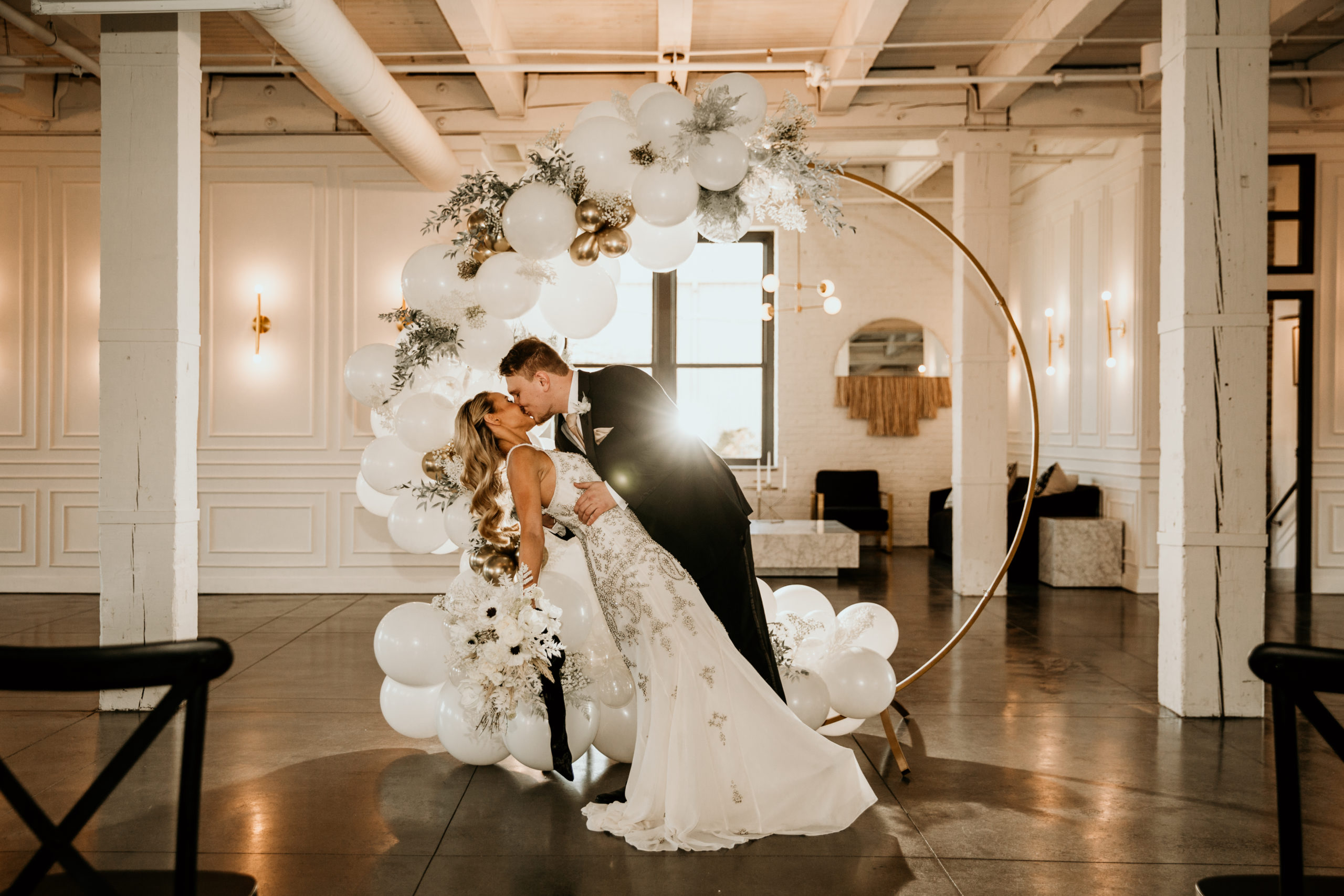 bride and groom kissing in front of a balloon arch and chicago wedding venue company 251.