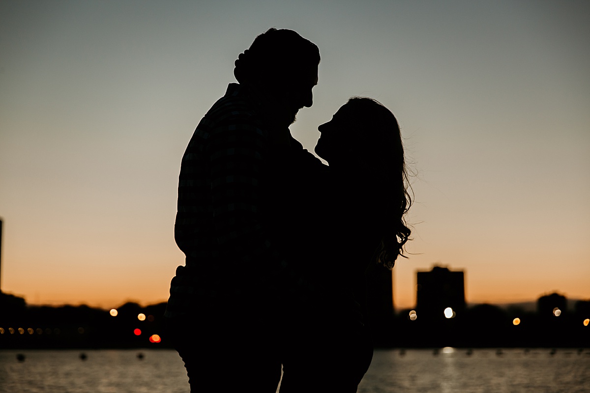 Silhouette of a couple looking at each other with the city of chicago behind them at sunset.