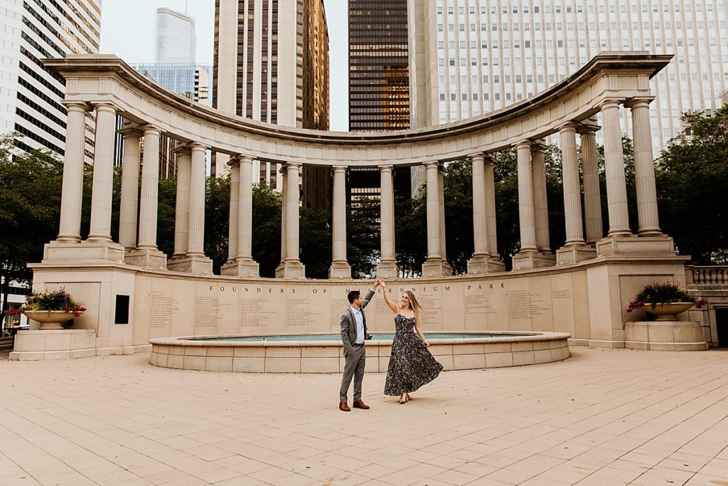 Guy spinning a girl in a dress in front of the Millennium monument at millennium park