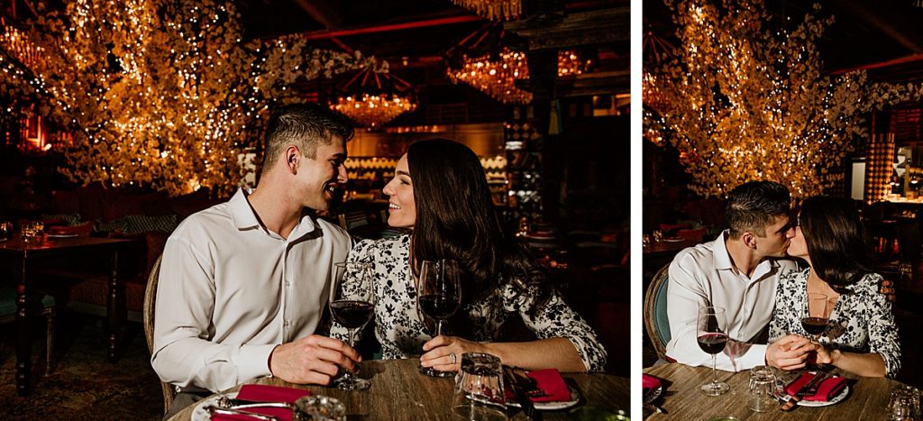 Man and woman looking at each other sitting next to each other at a restaurant clinking their wine. 