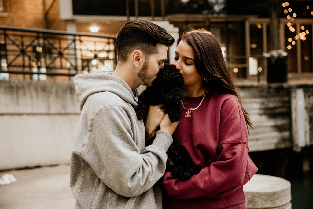 Couple's engagement photos kissing their small dog at the Ogden Slip in Chicago