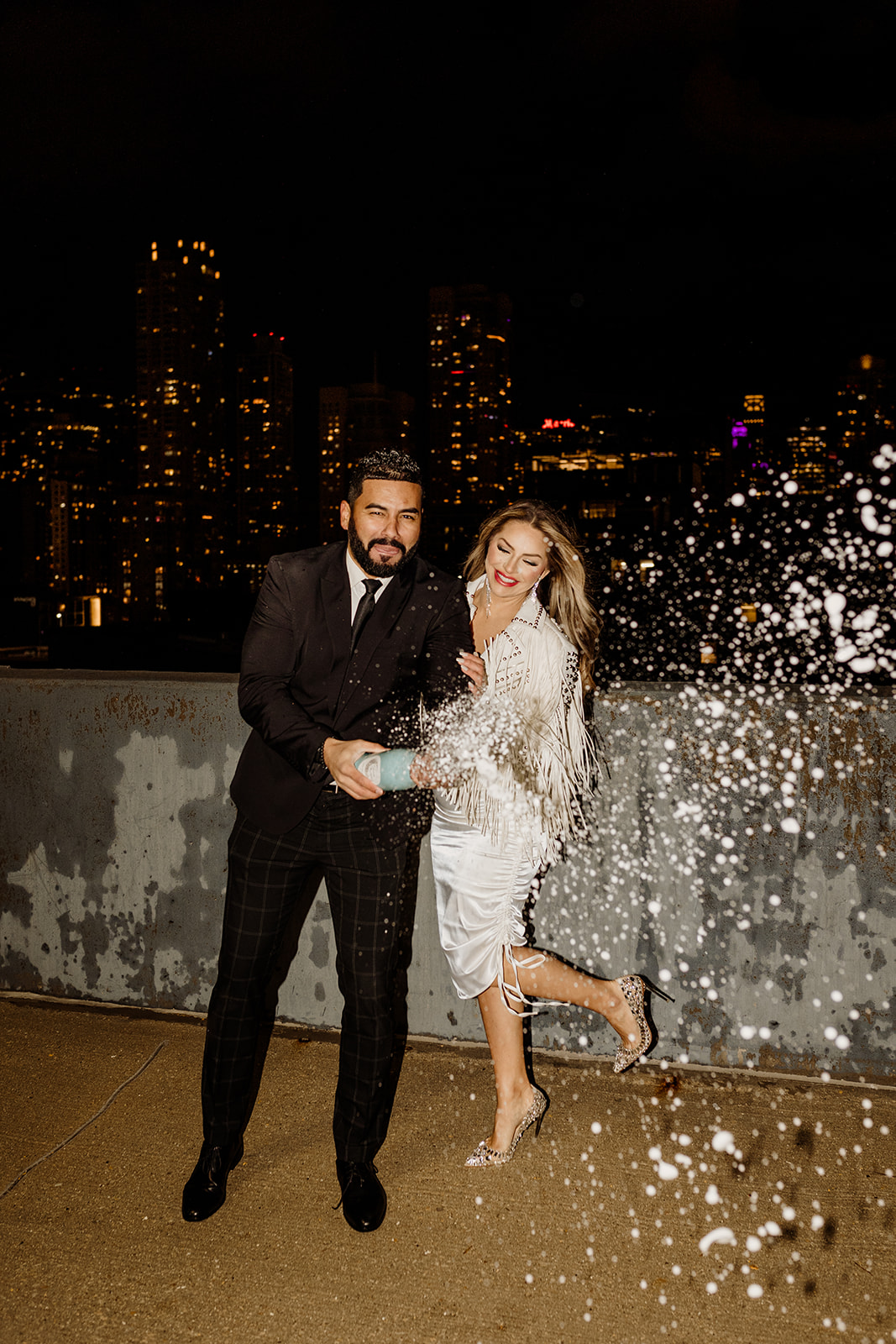 engaged couple in downtown chicago with city skyline popping champagne