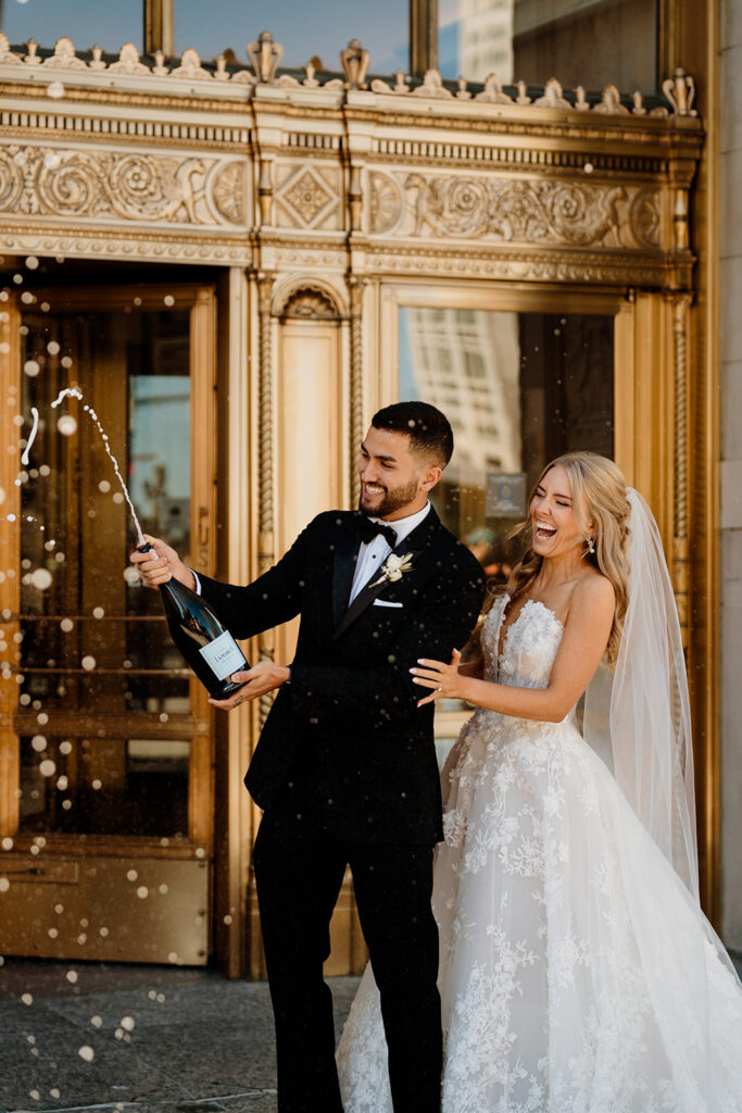 bride and groom pop champagne on morning of wedding day