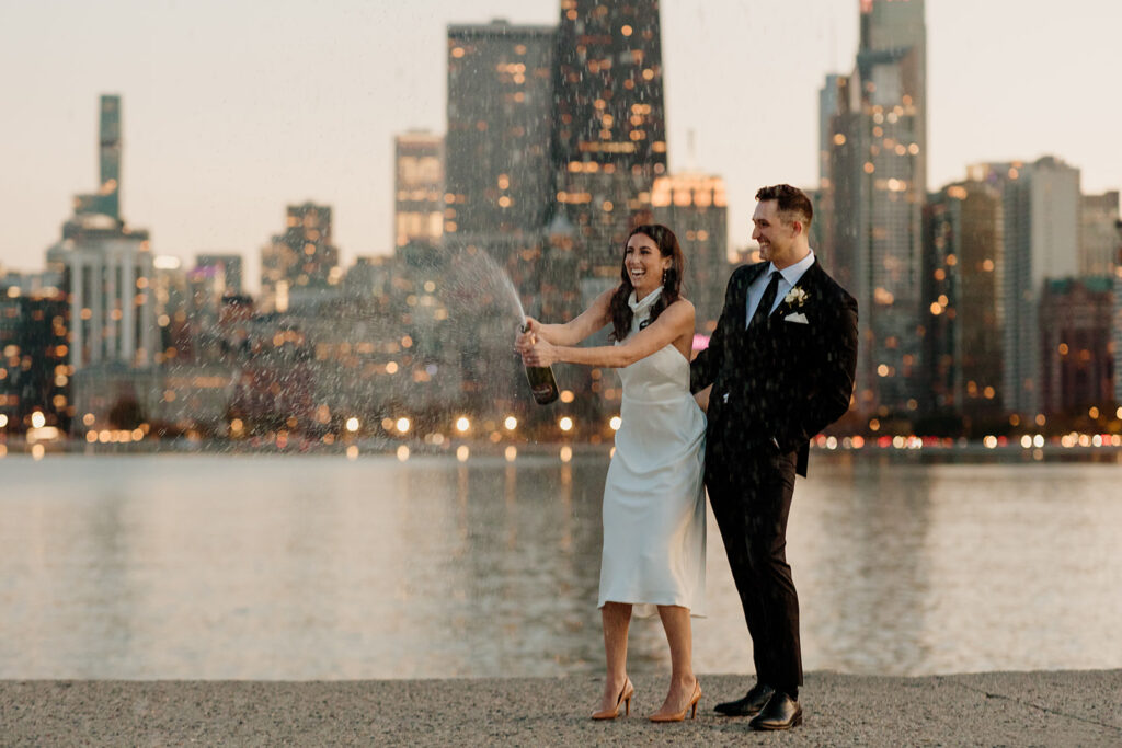 engaged couple pops champagne by chicago skyline