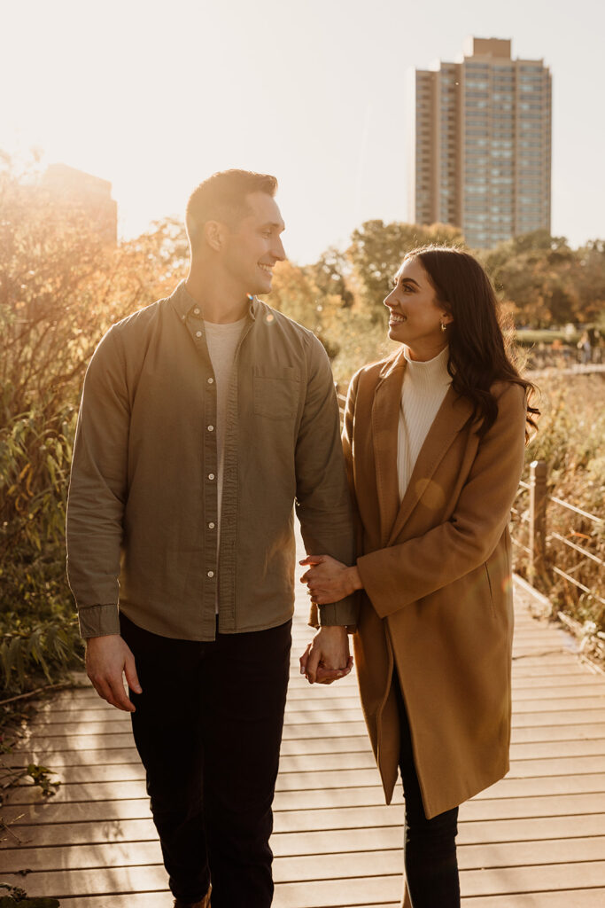 engaged couple in fall leaves at sunset golden hour