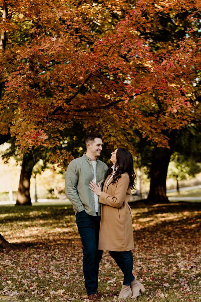 engaged couple in fall leaves at a park